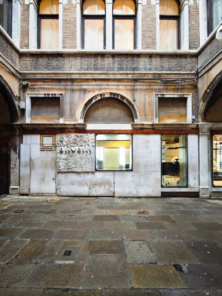 Fachada lateral del Negozio Olivetti, integración de arquitectura moderna en entorno histórico.